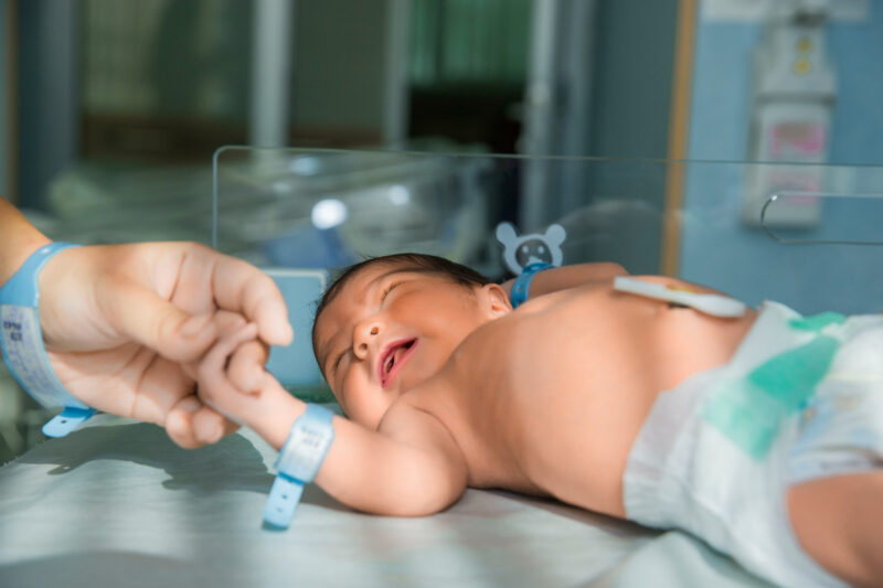 nurses for newborns holding infant's hand in an incubator