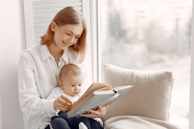 A nurses for newborns reading a book to an infant.  