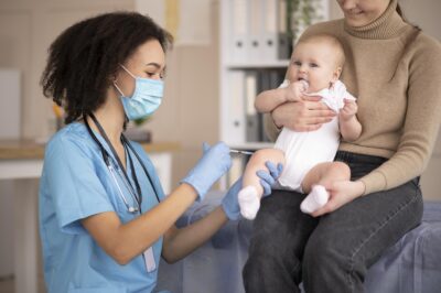 A nursing assistant applying medicine to a baby